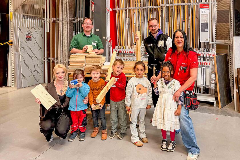Eine Gruppe Kinder, drei Erzieher*innen und ein Mitarbeiter von hagebaumarkt lächeln in die Kamera.
